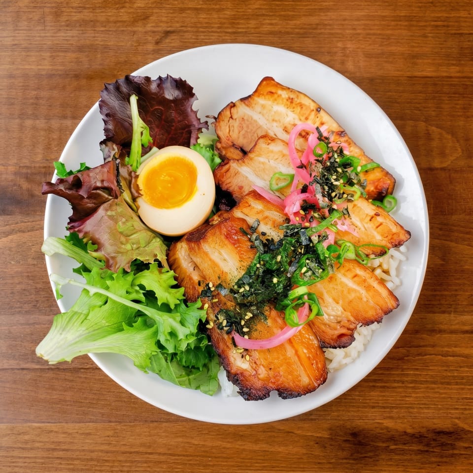A white bowl of chashu pork, rice, soft-boiled egg, mixed greens, and pickled onions.